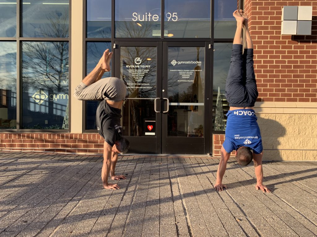 Two Evolve To Fit coaches doing handstands in front of Arlington, VA fitness center—showcasing mobility, strength, and nervous system-based training